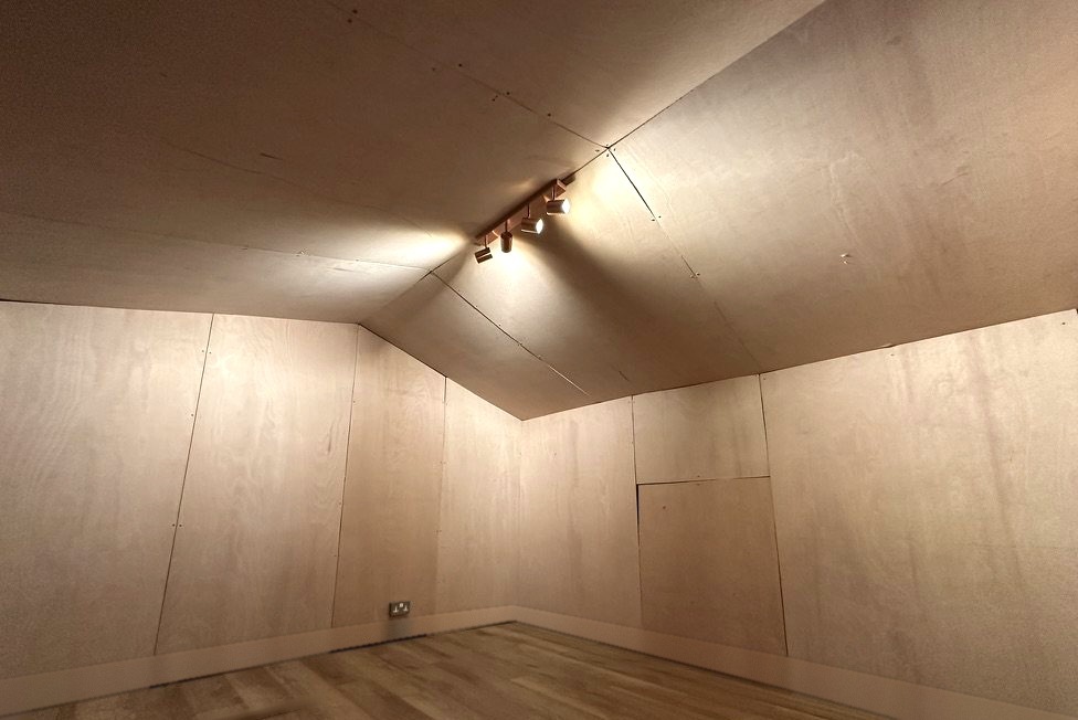 The same room lined in ply with track lighting