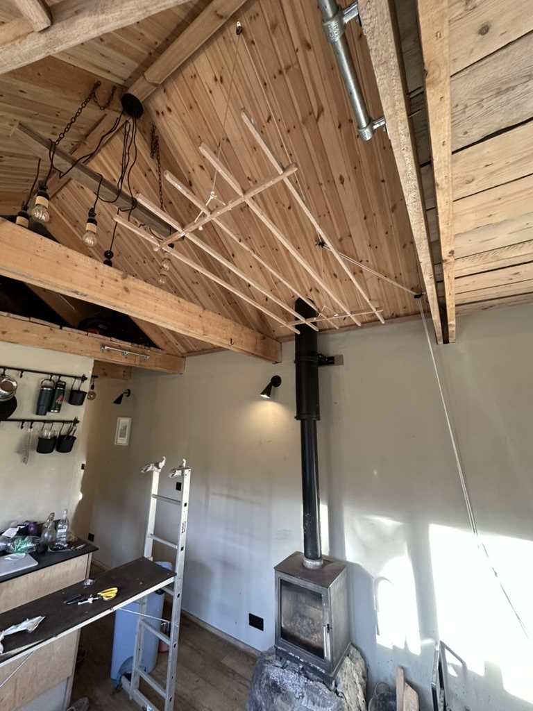 Ceiling-hung timber clothes airer in a pine-lined room